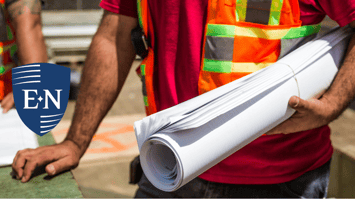 A construction worker holding documents about risk management services.