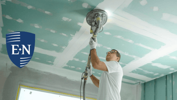 A 1099 contractor sanding the ceiling of a building.